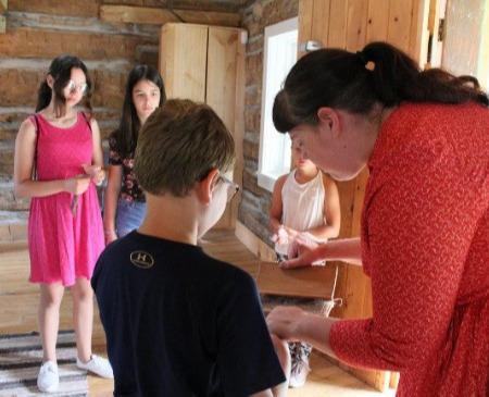 Museum staff showing a child a craft while other children watch